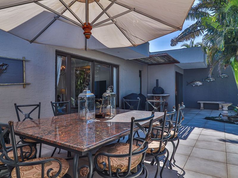 A spacious covered patio area featuring tiled flooring, a built-in pizza oven, and direct access to the interior through large sliding glass doors.