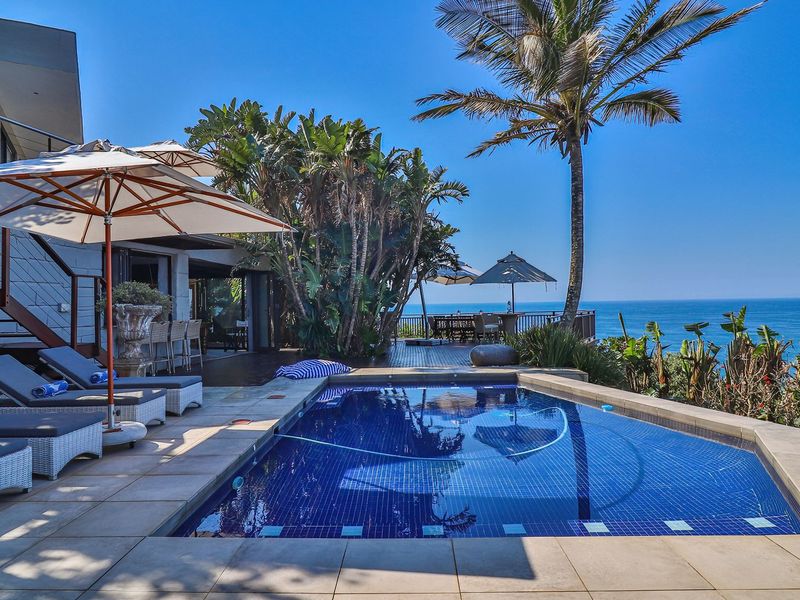 Outdoor pool area featuring a tiled swimming pool, timber decking, and expansive ocean views, perfect for coastal living and entertainment.