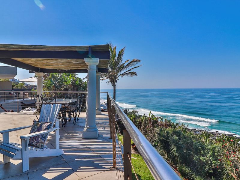 Spacious covered patio featuring tiled flooring, classical columns, and a stainless steel balustrade, offering expansive, unobstructed views of the ocean.