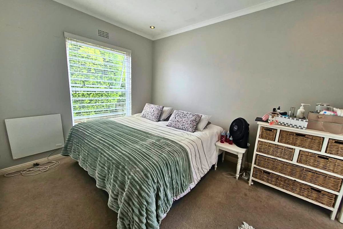 A comfortable bedroom featuring neutral wall tones, carpeted flooring, recessed lighting, and a wall-mounted electric heater for climate control.