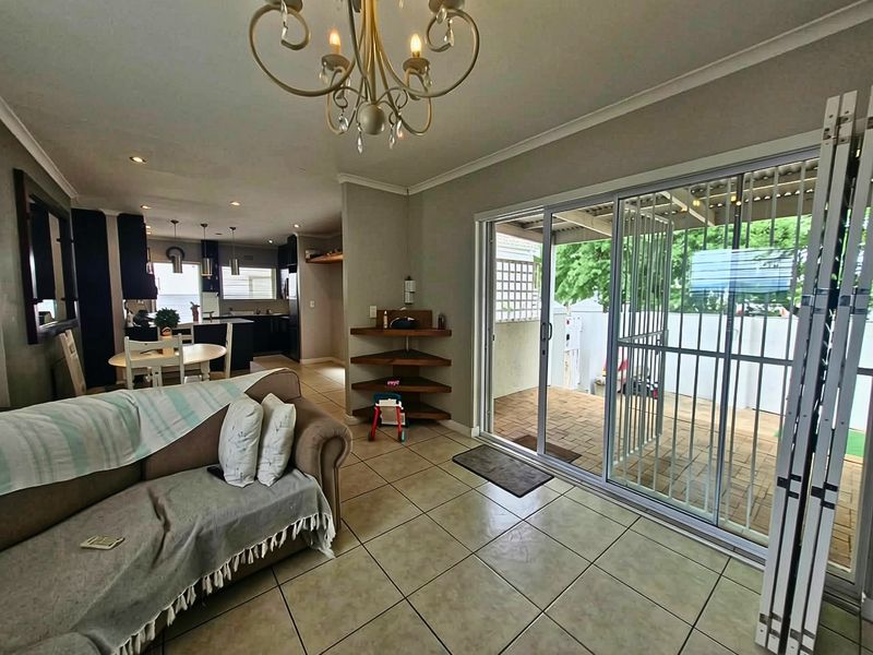 Open-plan living area featuring tiled floors, built-in corner shelving, and large sliding glass doors providing direct access to the outdoor patio area.