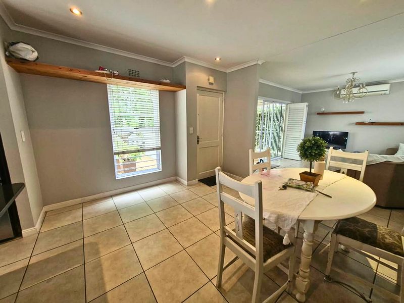 Open-plan living and dining area featuring neutral tiled flooring, recessed lighting, and sliding glass doors leading to an outdoor space.