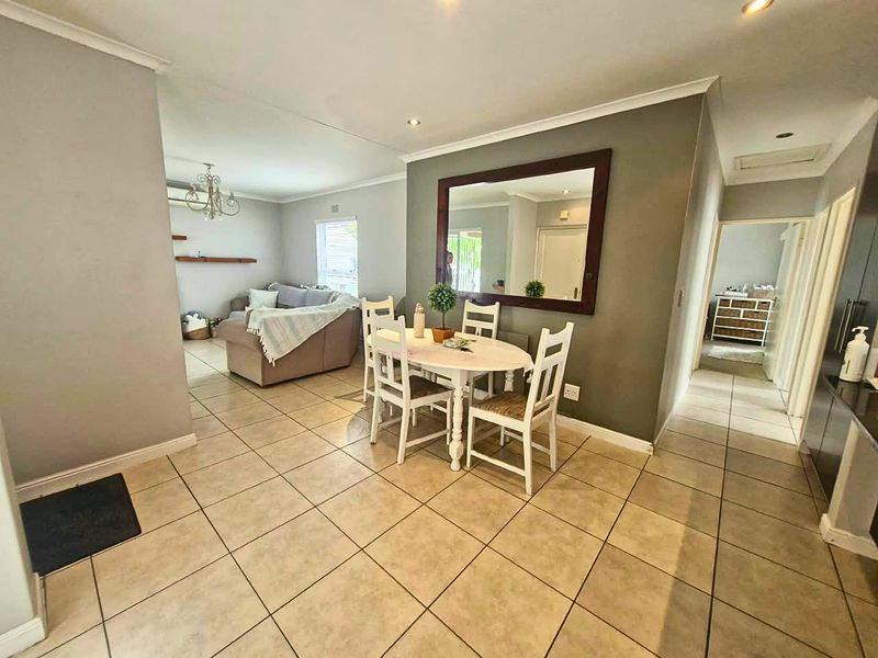 Open plan living and dining area featuring neutral tiled flooring, recessed lighting, and a feature wall with a large mirror.