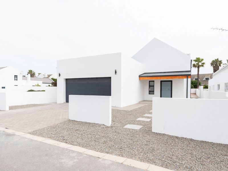 Modern contemporary house exterior featuring a clean white facade, double garage, paved driveway, and a welcoming covered entrance area.