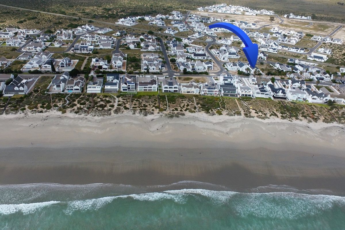 Aerial view of a coastal residential estate situated directly along the beachfront, showcasing the property's prime location and surrounding neighborhood.
