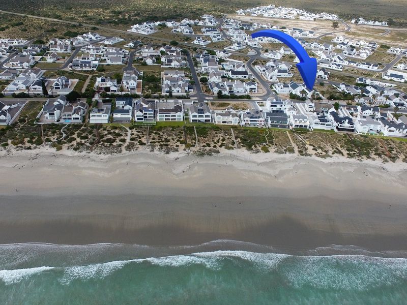 Aerial view of a coastal residential estate situated directly along the beachfront, showcasing the property's prime location and surrounding neighborhood.