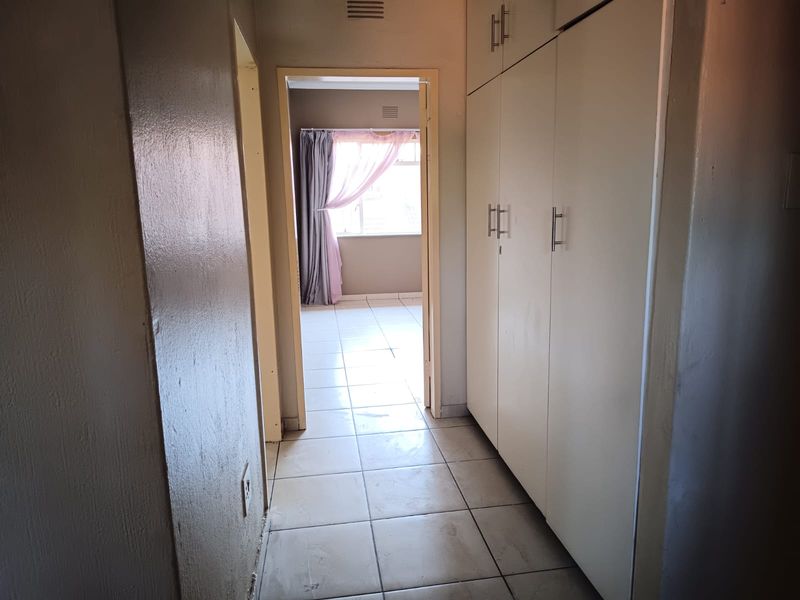 A functional hallway featuring built-in storage cupboards and tiled flooring, providing access to adjacent living spaces.