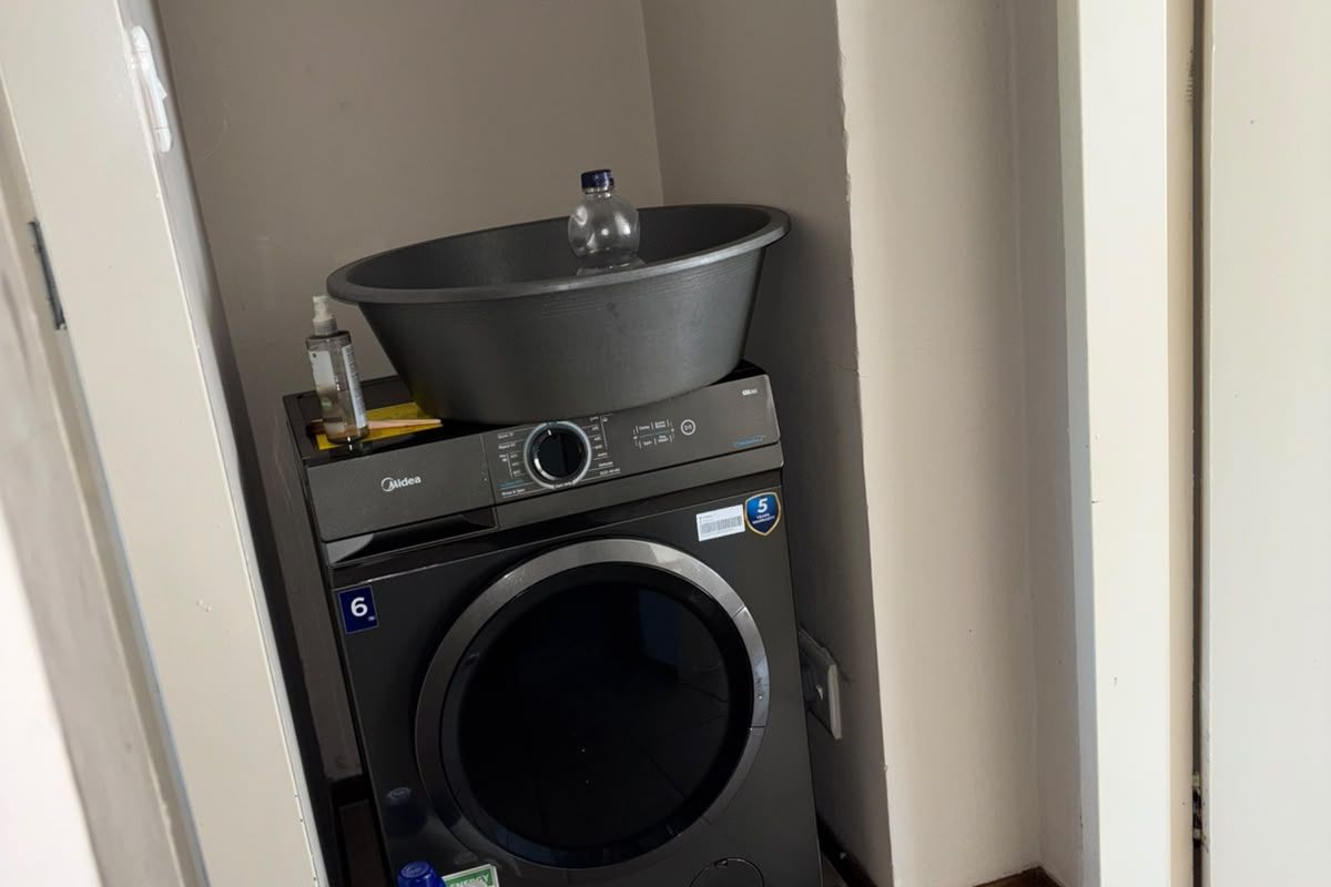 A compact laundry alcove featuring tiled flooring and space for a washing machine.