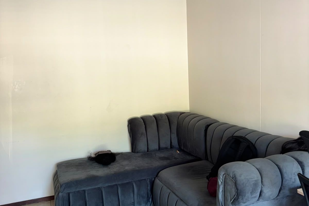 A living room area featuring tiled flooring and a simple ceiling light fixture, currently showing signs of wear on the wall surfaces.