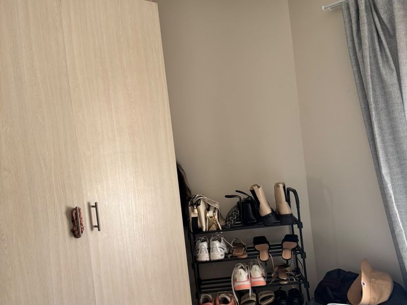 A bedroom featuring a light wood-finish built-in wardrobe and a curtain rail, providing functional storage and window treatment.