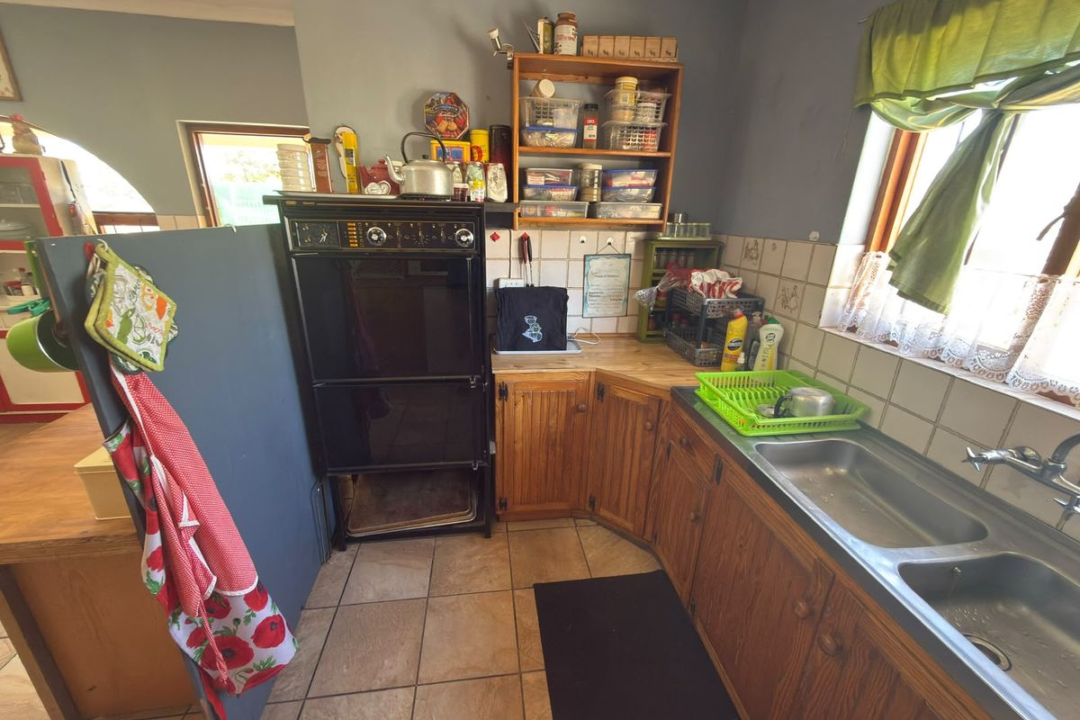 A dated kitchen featuring wooden cabinetry, a built-in oven, and a double sink with tiled splashbacks and flooring.