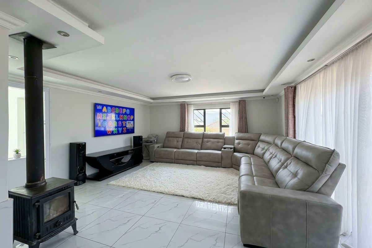 Spacious living room featuring modern marble-look tiled flooring, a freestanding fireplace, and recessed ceiling lighting, creating a bright and comfortable atmosphere.