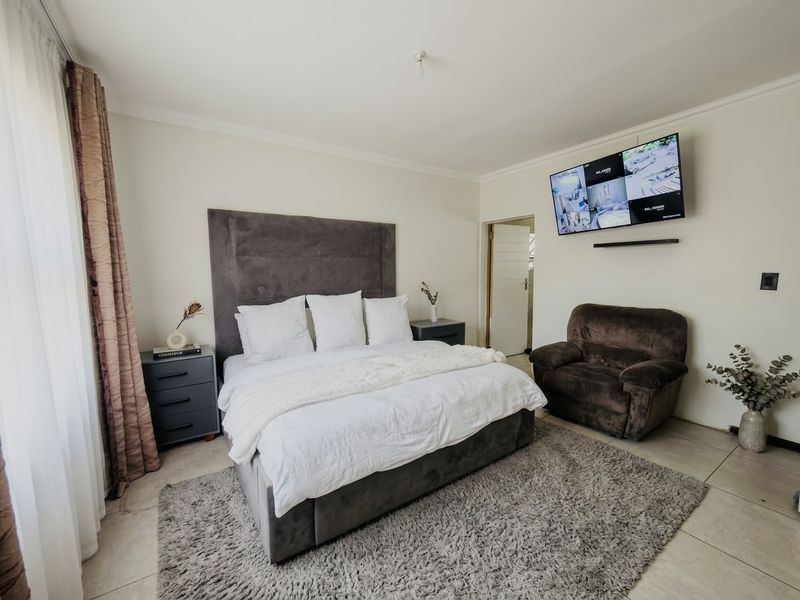 A well-maintained bedroom featuring neutral wall tones, tiled flooring, and decorative cornice detailing, providing a comfortable and functional living space.