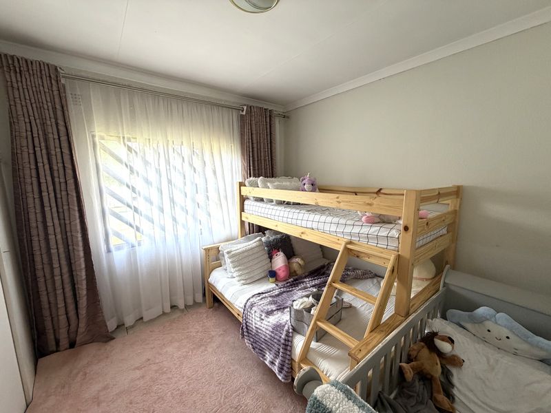 A functional bedroom featuring a window with security bars and installed curtain rails, providing a comfortable space for rest.