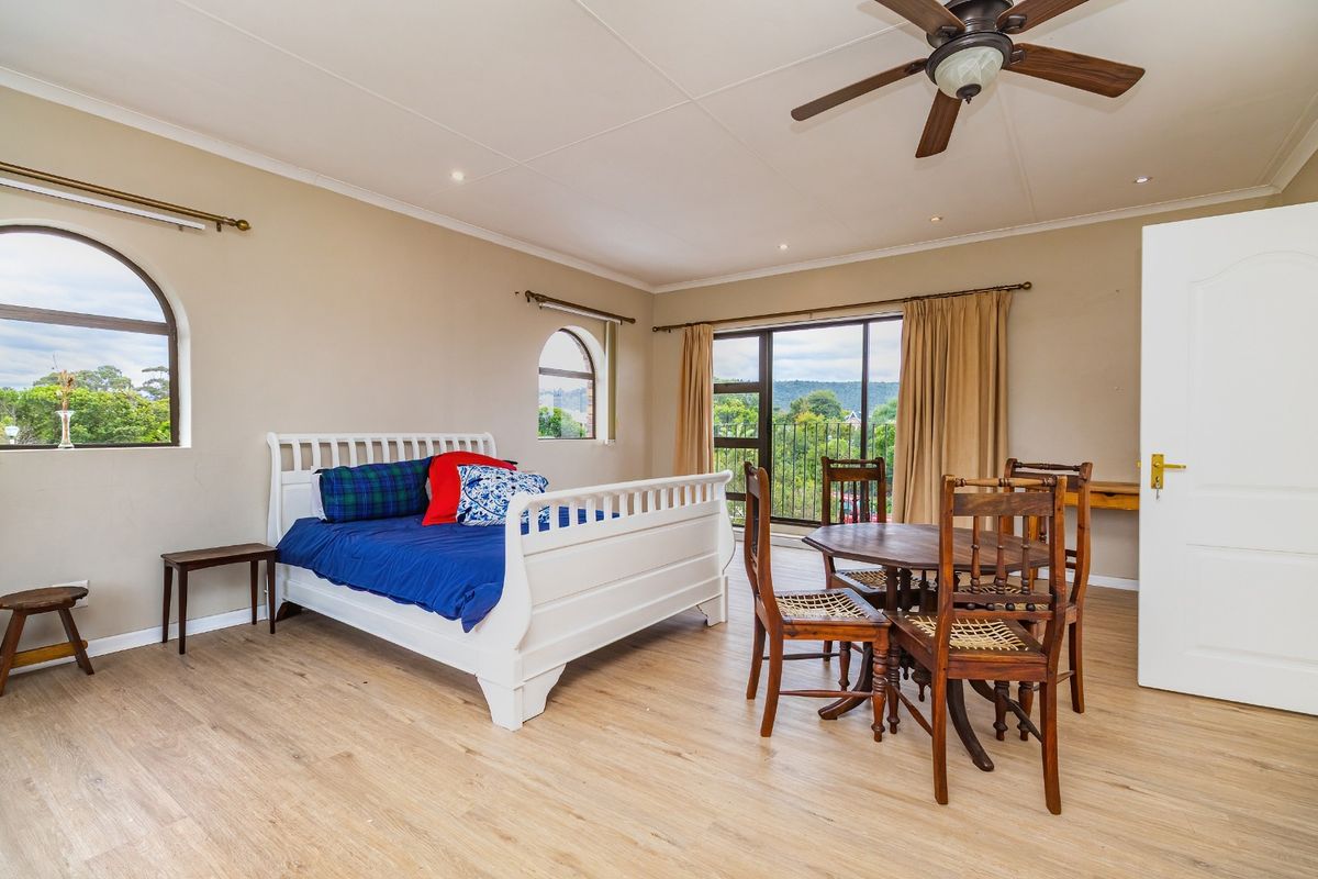 Spacious bedroom featuring laminate flooring, a ceiling fan, arched windows, and a sliding glass door leading to a balcony with scenic views.