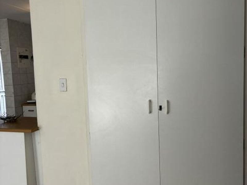 A hallway area featuring a large built-in cupboard with white doors and tiled flooring.