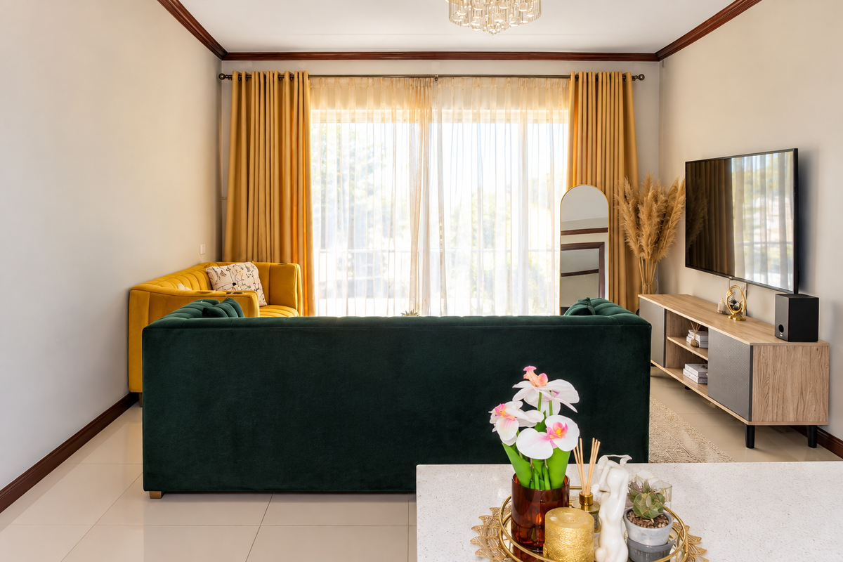 A well-maintained living room featuring tiled flooring, crown molding, and large sliding glass doors that provide ample natural light.