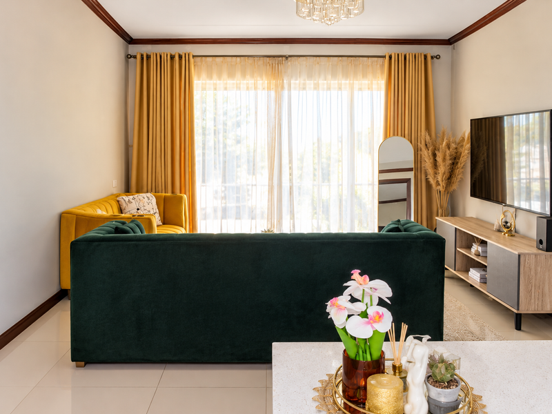 A well-maintained living room featuring tiled flooring, crown molding, and large sliding glass doors that provide ample natural light.
