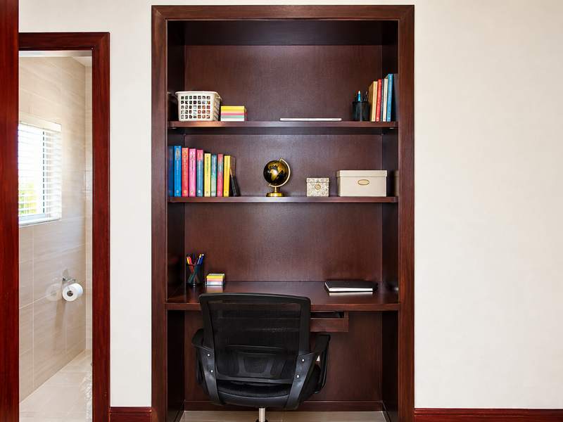 A dedicated study nook featuring a built-in dark timber desk and integrated shelving unit, finished with matching timber trim.