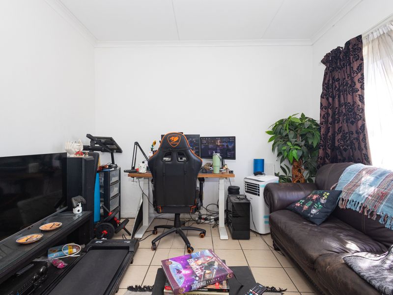 A functional living area featuring tiled flooring and natural light access, currently utilized as a multi-purpose space.