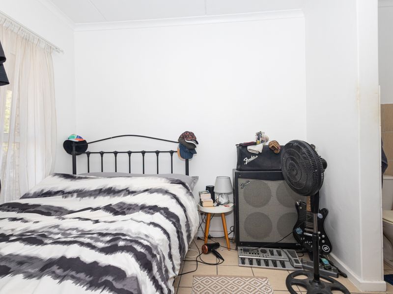A bedroom featuring tiled flooring and an en-suite toilet, requiring cosmetic updates to improve the overall condition and appeal.