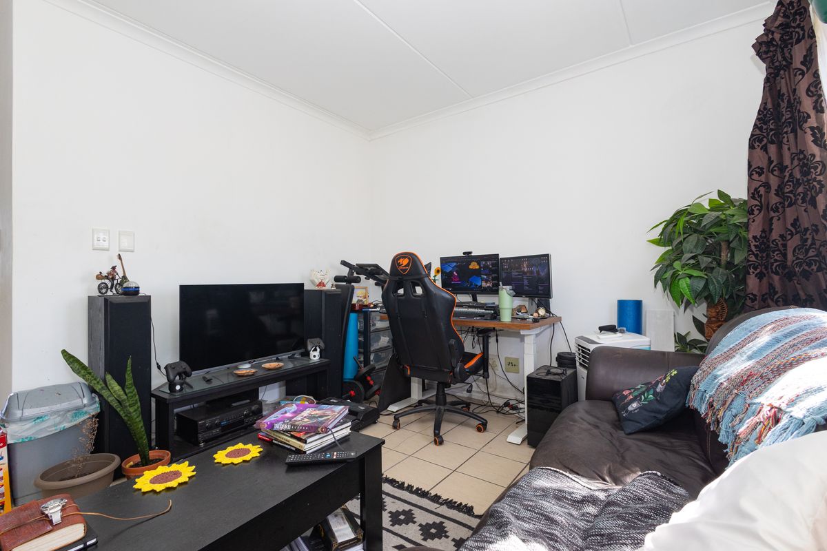 A functional living area featuring tiled flooring and coved ceilings, currently utilized as a multi-purpose space.