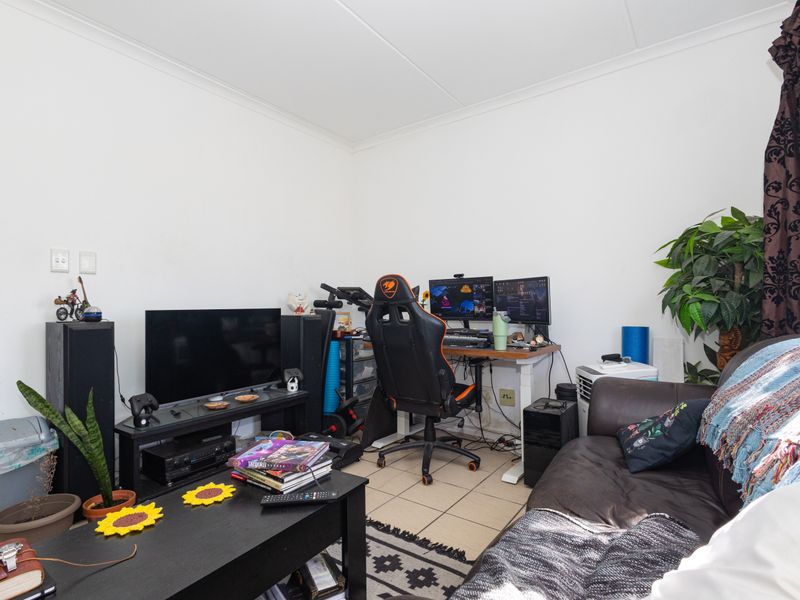 A functional living area featuring tiled flooring and coved ceilings, currently utilized as a multi-purpose space.