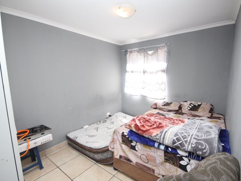 A bedroom featuring tiled flooring and grey painted walls, offering a functional space ready for personalization and cosmetic updates.