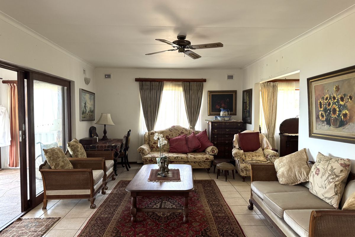 A spacious living room featuring tiled flooring, a ceiling fan, and large sliding glass doors that provide access to the outdoor area.