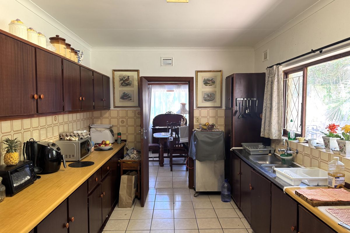 A functional galley-style kitchen featuring dark wood cabinetry, laminate countertops, and tiled flooring, offering a classic layout with potential for modern updates.