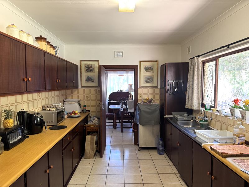 A functional galley-style kitchen featuring dark wood cabinetry, laminate countertops, and tiled flooring, offering a classic layout with potential for modern updates.