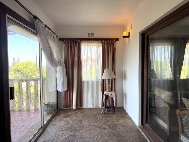 A sunroom or enclosed patio area featuring stone flooring, large sliding glass doors, and natural light, offering a transition space between indoor and outdoor areas.