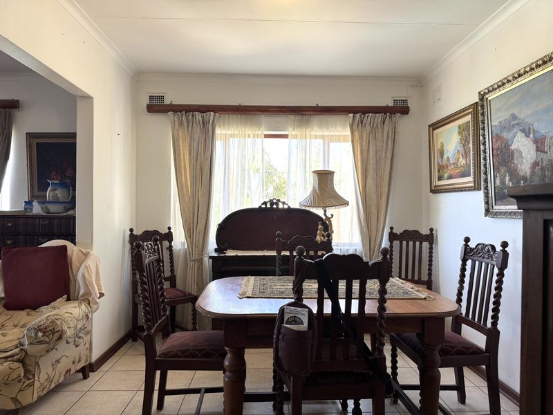 A traditional dining room featuring tiled flooring and a large window with curtain treatments, offering a functional space for family meals.