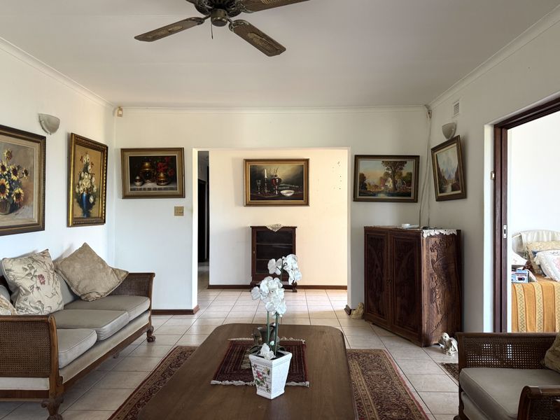 A spacious living room featuring tiled flooring, a ceiling fan, and neutral wall finishes, providing a comfortable and functional living area.