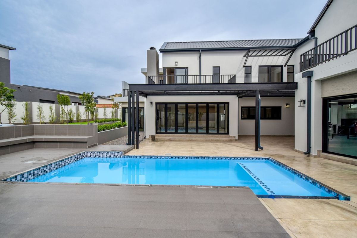 A modern rear exterior featuring a swimming pool, tiled patio area, and a covered pergola structure attached to the double-story residence.