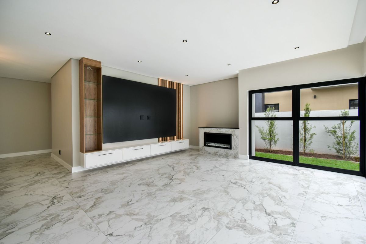 Modern living room featuring large-format marble-look floor tiles, a built-in media wall with integrated shelving, and a sleek fireplace overlooking a private garden.