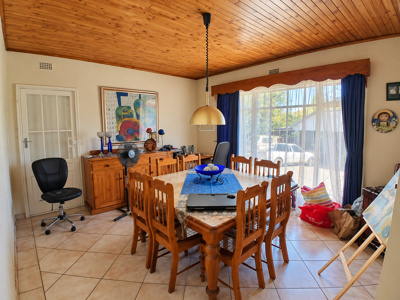 A dining room featuring a warm timber tongue and groove ceiling, ceramic tiled flooring, and a large sliding glass door providing natural light.
