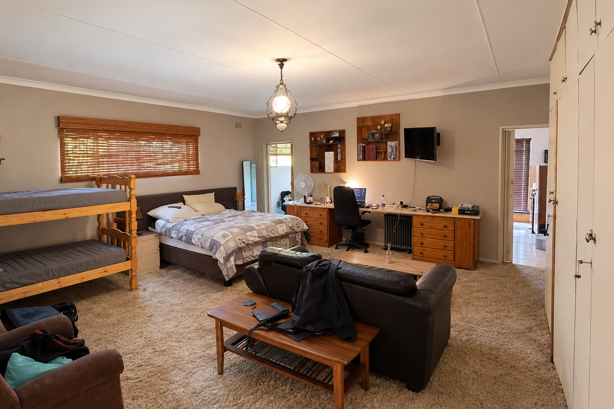Spacious bedroom featuring built-in cupboards, carpeted flooring, and bamboo blinds, offering a versatile layout with ample storage space.
