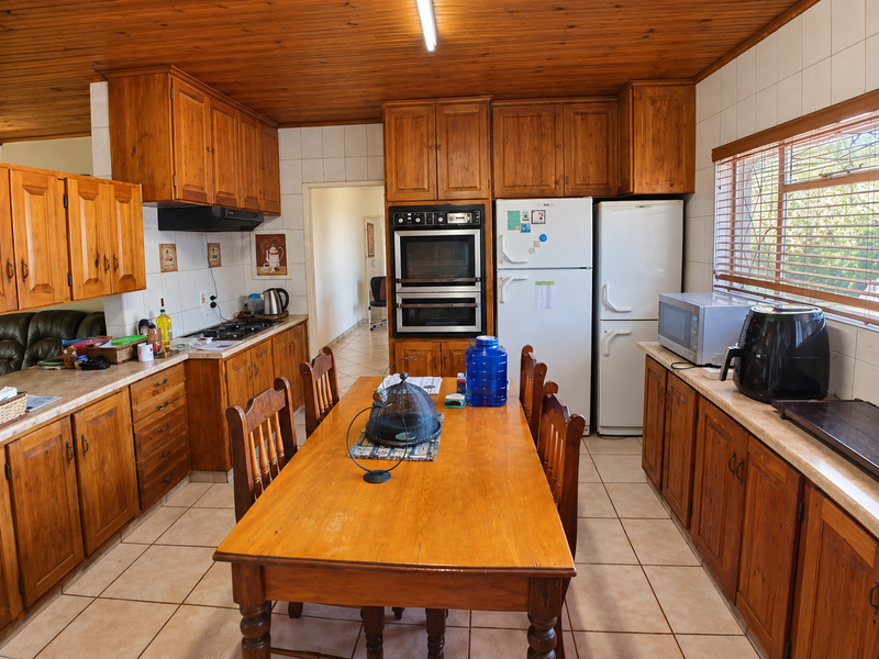 Spacious kitchen featuring extensive wooden cabinetry, built-in double oven, gas hob, and tiled flooring, offering a traditional aesthetic with ample storage and workspace.
