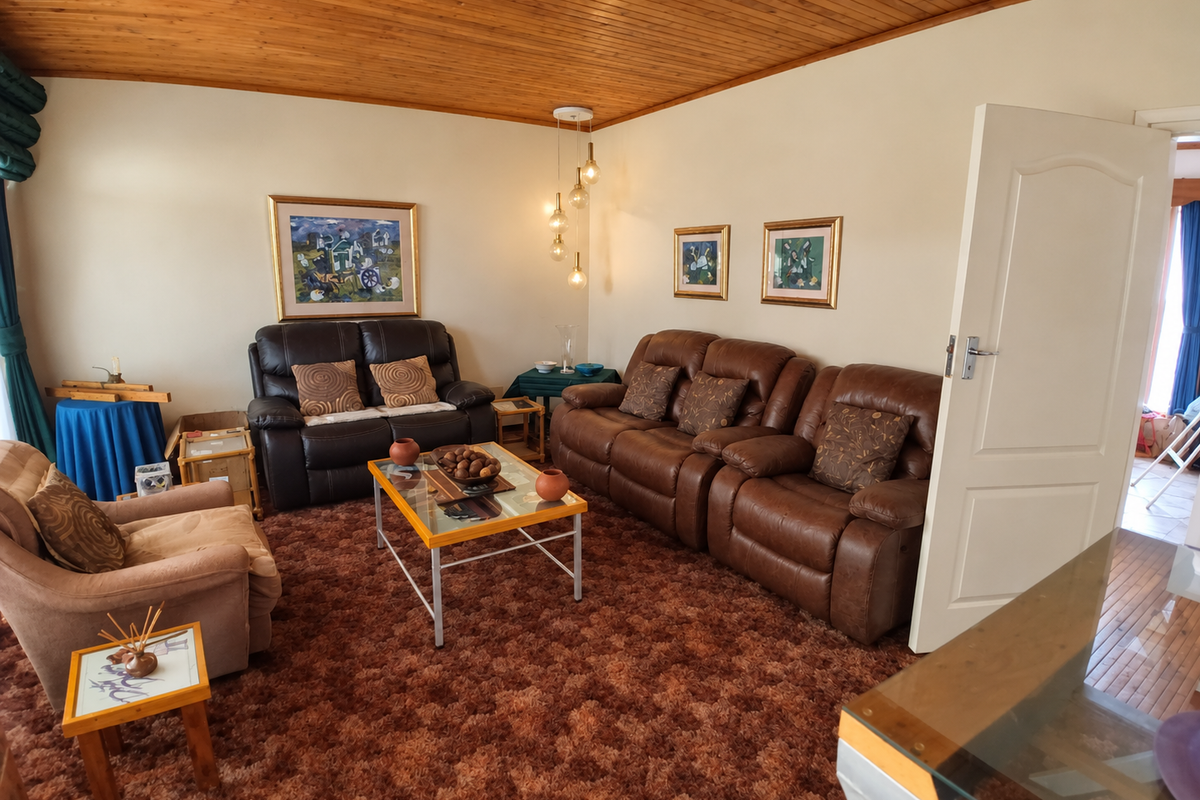 A living room featuring a timber-clad ceiling and carpeted flooring, offering a traditional layout with potential for modernization.