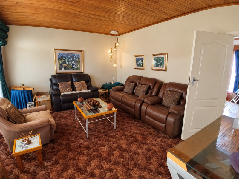 A living room featuring a timber-clad ceiling and carpeted flooring, offering a traditional layout with potential for modernization.