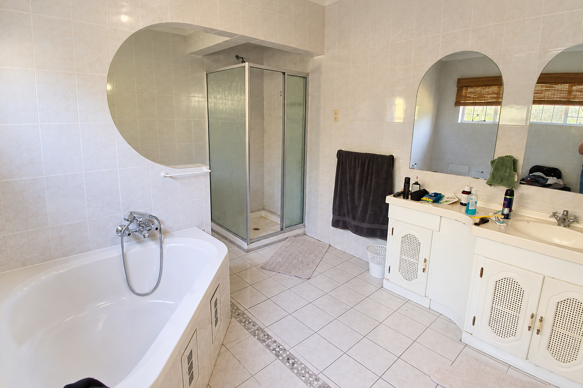 Spacious bathroom featuring a built-in bathtub, separate shower enclosure, and a dual-vanity unit with integrated mirrors and tiled finishes throughout.
