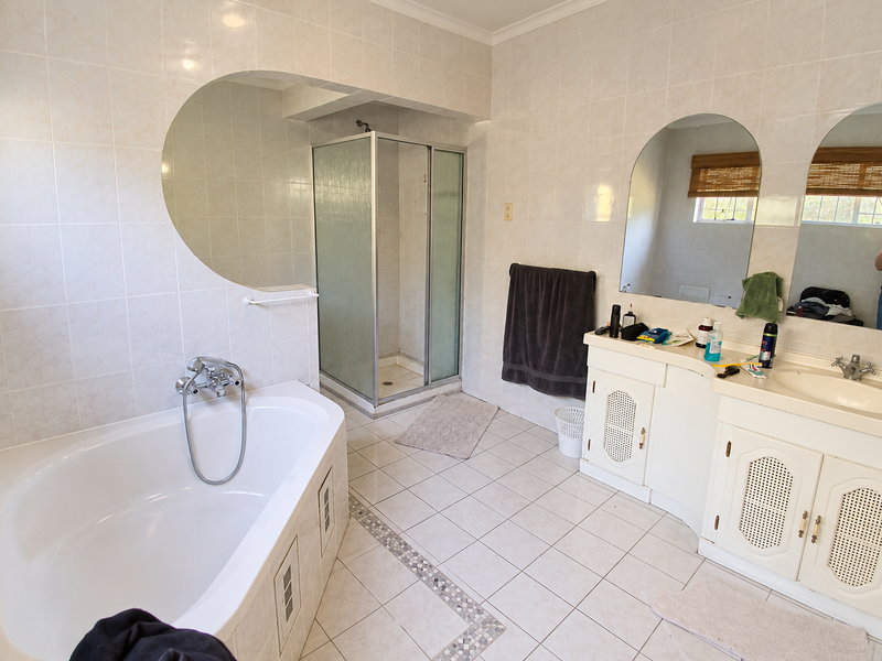 Spacious bathroom featuring a built-in bathtub, separate shower enclosure, and a dual-vanity unit with integrated mirrors and tiled finishes throughout.
