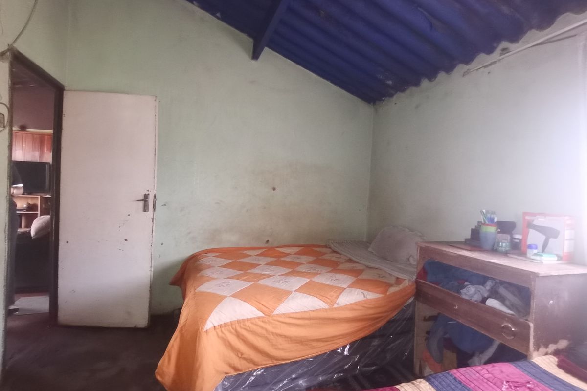A bedroom featuring exposed rafters and basic finishes, requiring cosmetic updates and maintenance to improve the overall condition and appeal.