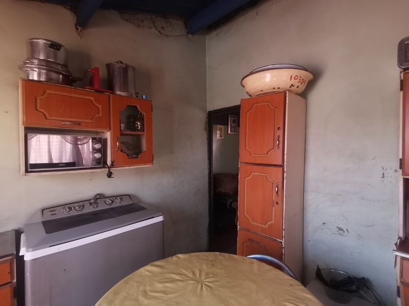 A dated kitchen area featuring built-in cabinetry and a built-in microwave, requiring significant cosmetic updates and wall repairs to improve the overall condition.