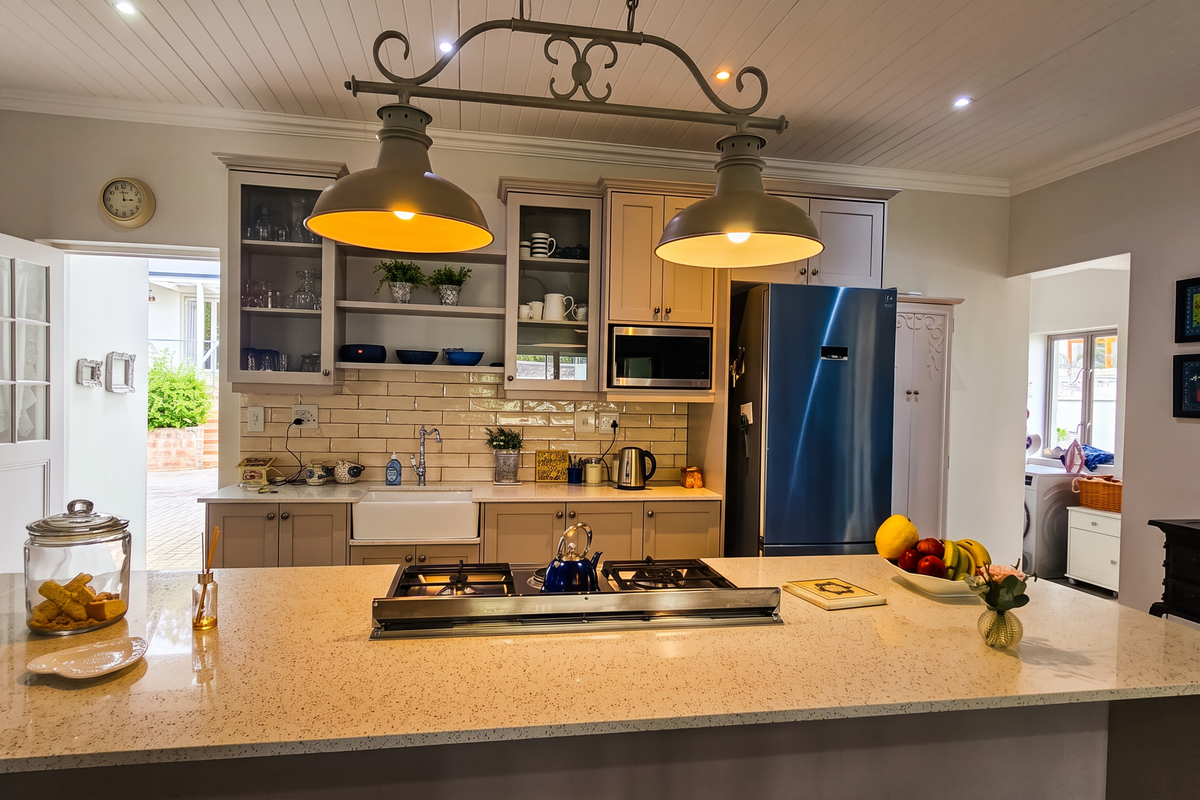 A well-appointed kitchen featuring a large central island with a gas hob, farmhouse sink, subway tile backsplash, and elegant shaker-style cabinetry.