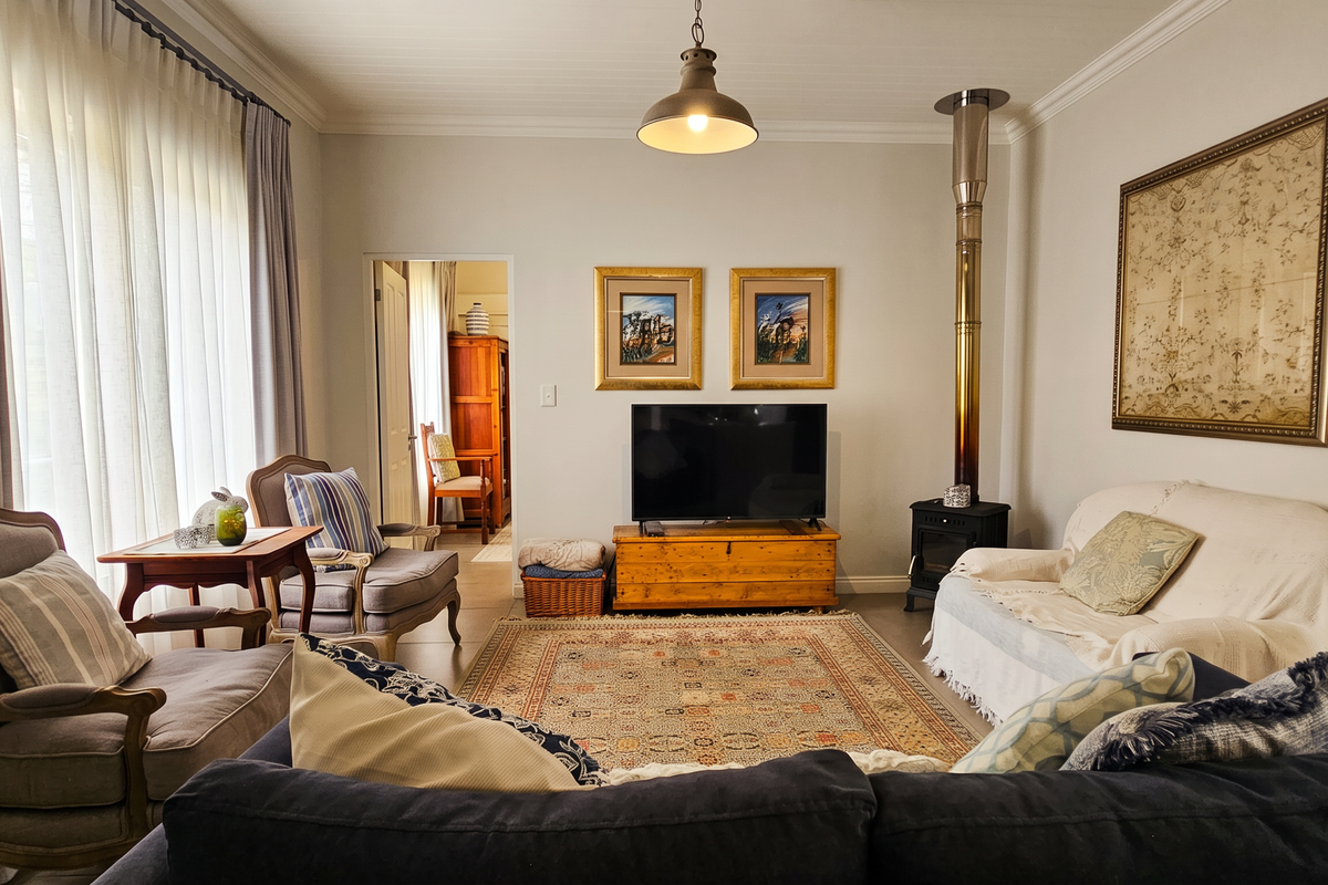 A comfortable living room featuring a freestanding fireplace with a flue pipe, tiled flooring, and classic ceiling cornicing.