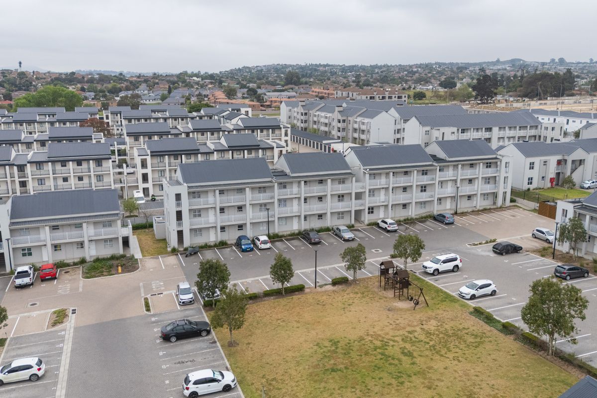 Aerial view of a modern residential apartment complex featuring multiple multi-story buildings, paved parking facilities, and landscaped communal areas.