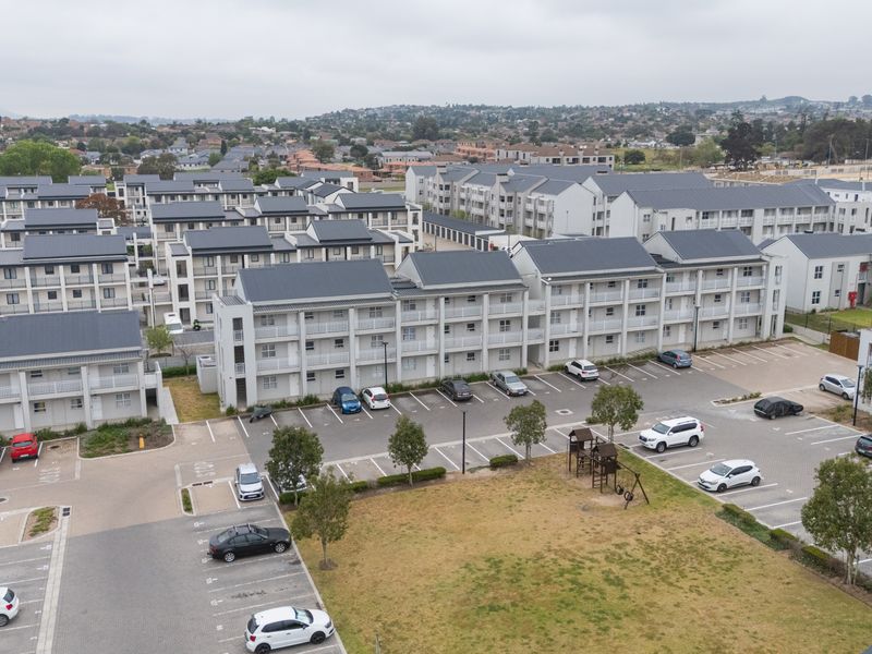 Aerial view of a modern residential apartment complex featuring multiple multi-story buildings, paved parking facilities, and landscaped communal areas.