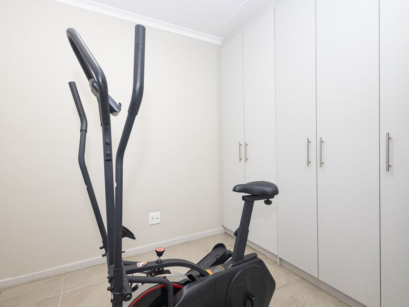 A bedroom featuring neutral walls, tiled flooring, and extensive built-in cupboard storage.